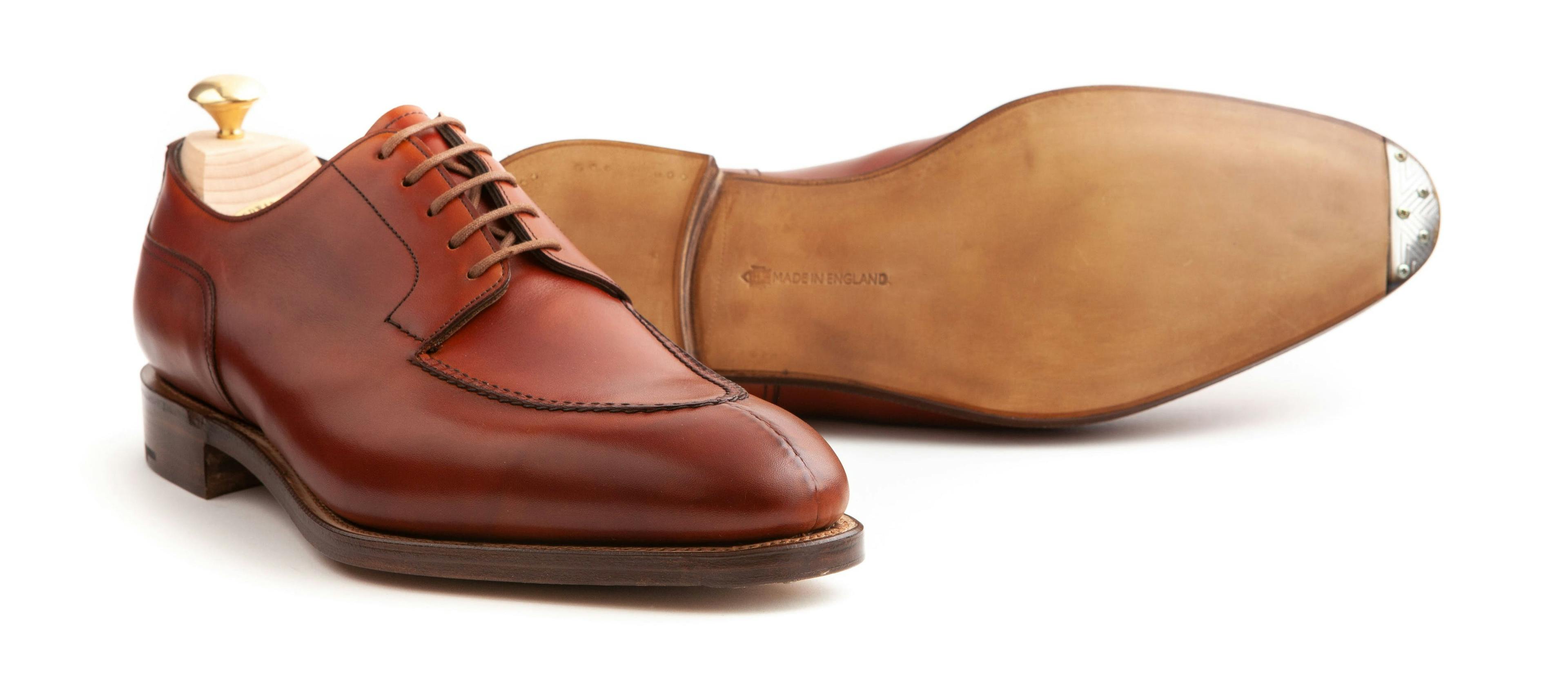 An Edward Green Dover in Redwood calf with a view of its single leather soles with metal toe plates.